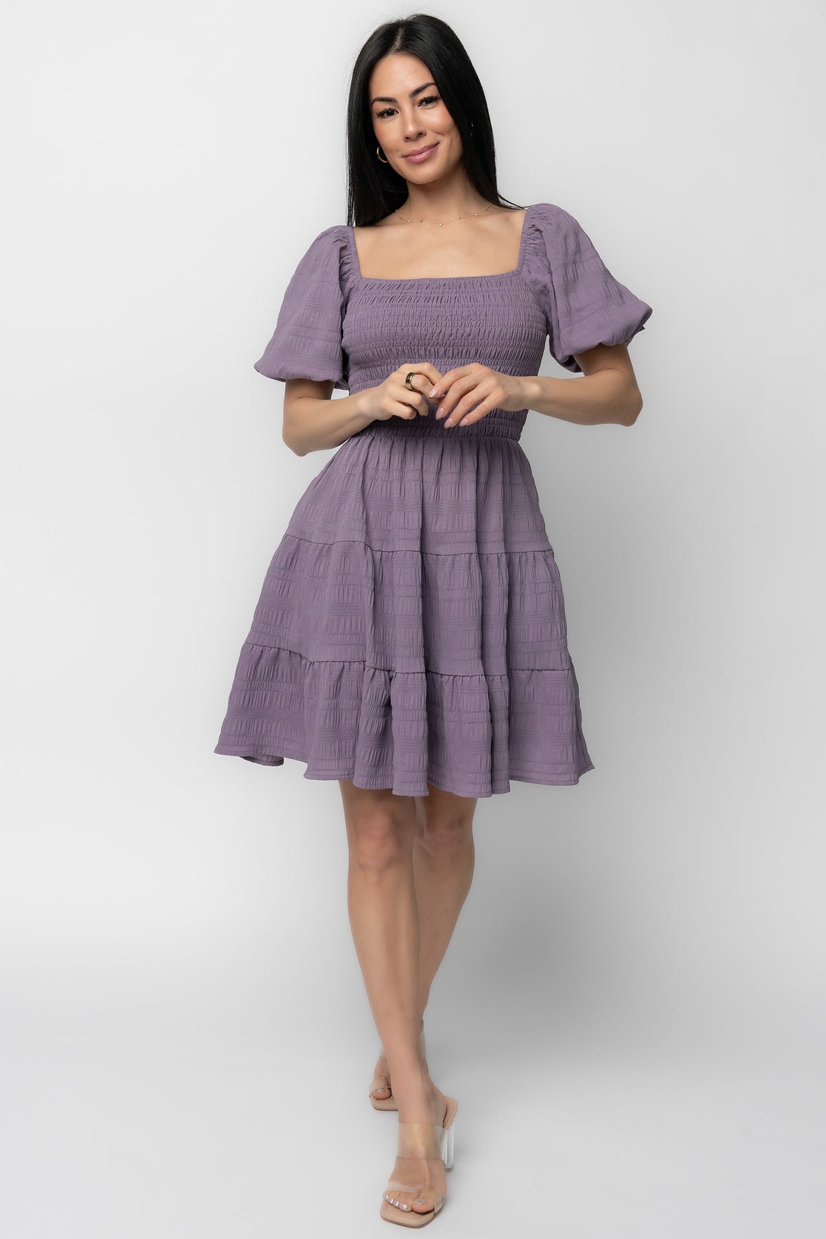 Front view of model wearing Daze Smocked Dress in dusty lavender showing square neckline, smocked bodice and three-tier short skirt.
