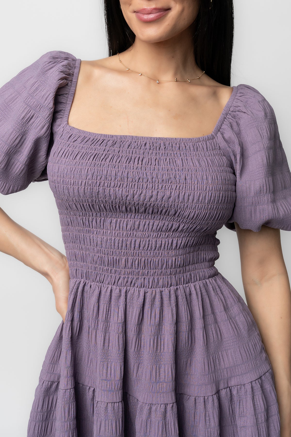 Side view showing hidden side pocket and three-tier short skirt on the Daze Smocked Dress in dusty lavender with soft drape.