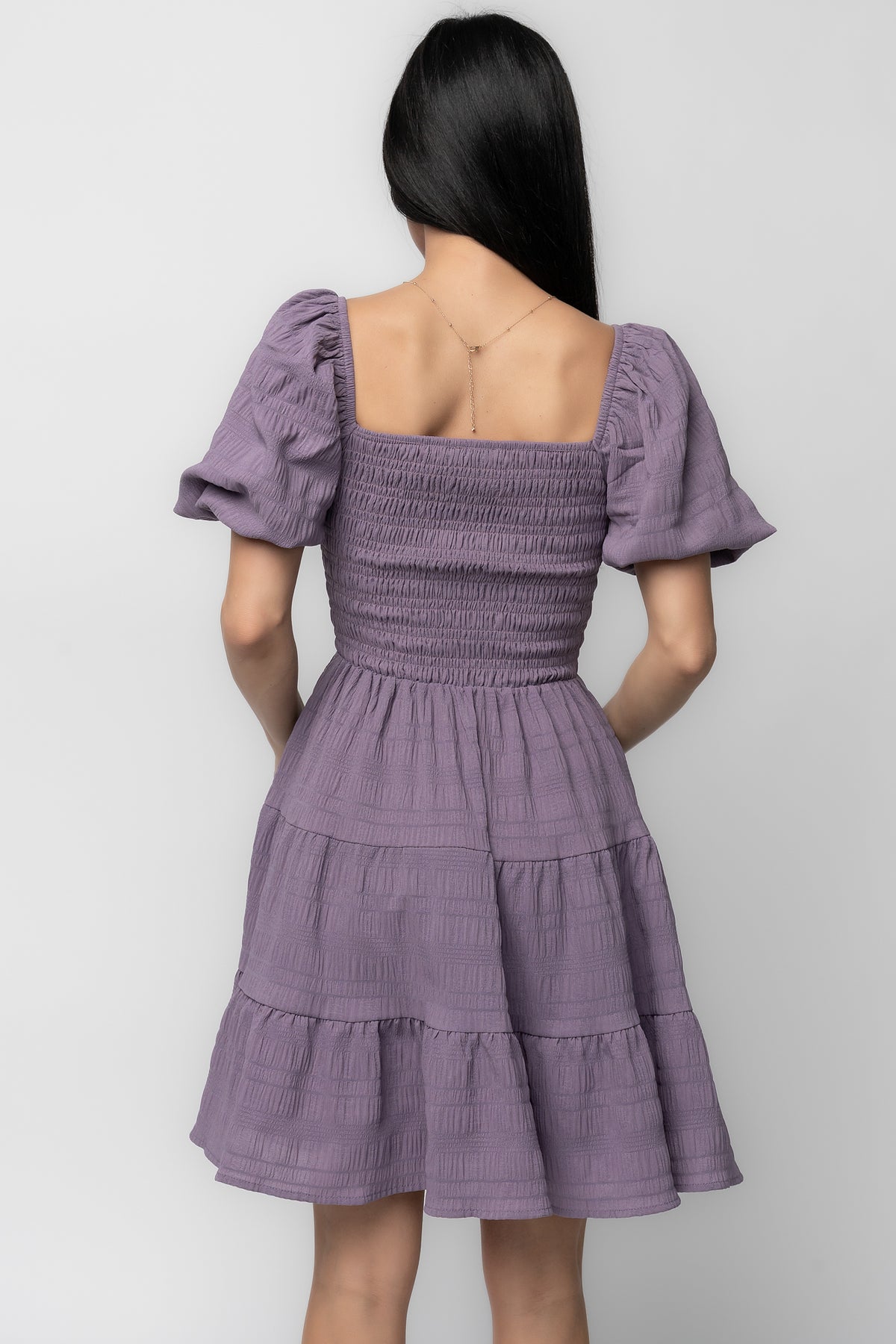Back view of dress in dusty lavender displaying tiered skirt hemline and lined interior for smooth fit and comfortable wear.
