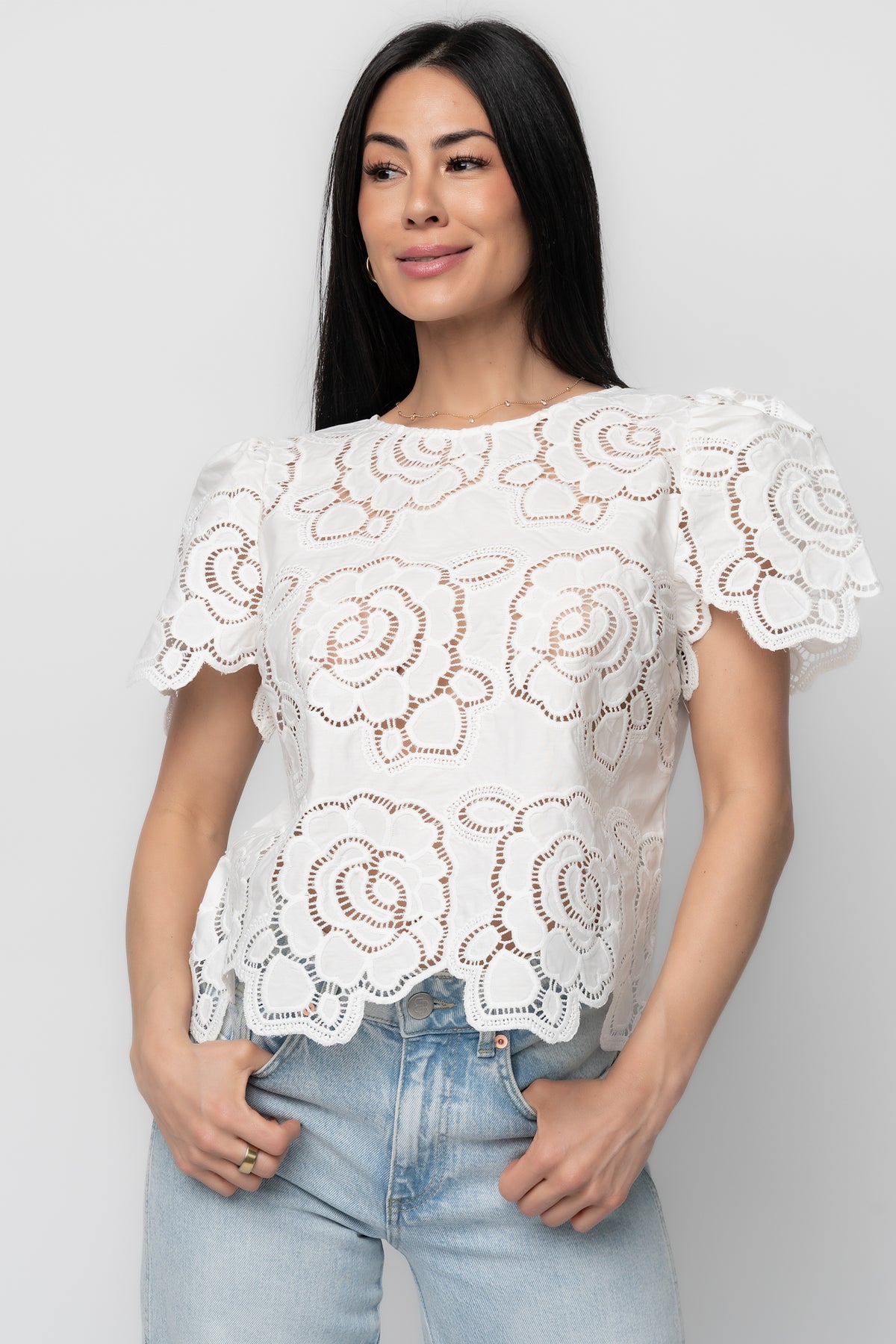 Studio shot of Delphine Floral Top laid flat, showing full front design, embroidered eyelet pattern, round neckline, and lightweight fabric composition.