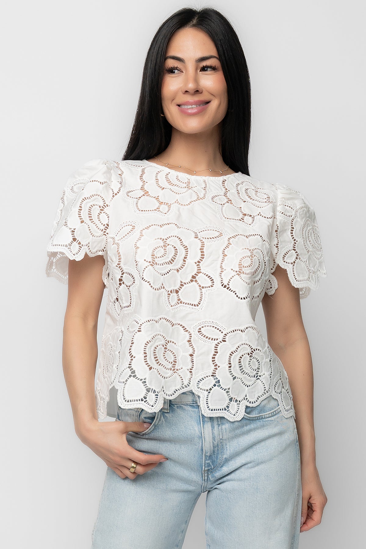 Front view of Delphine Floral Top in off-white on model, showing embroidered eyelet florals, round neckline, short sleeves, and relaxed fit.