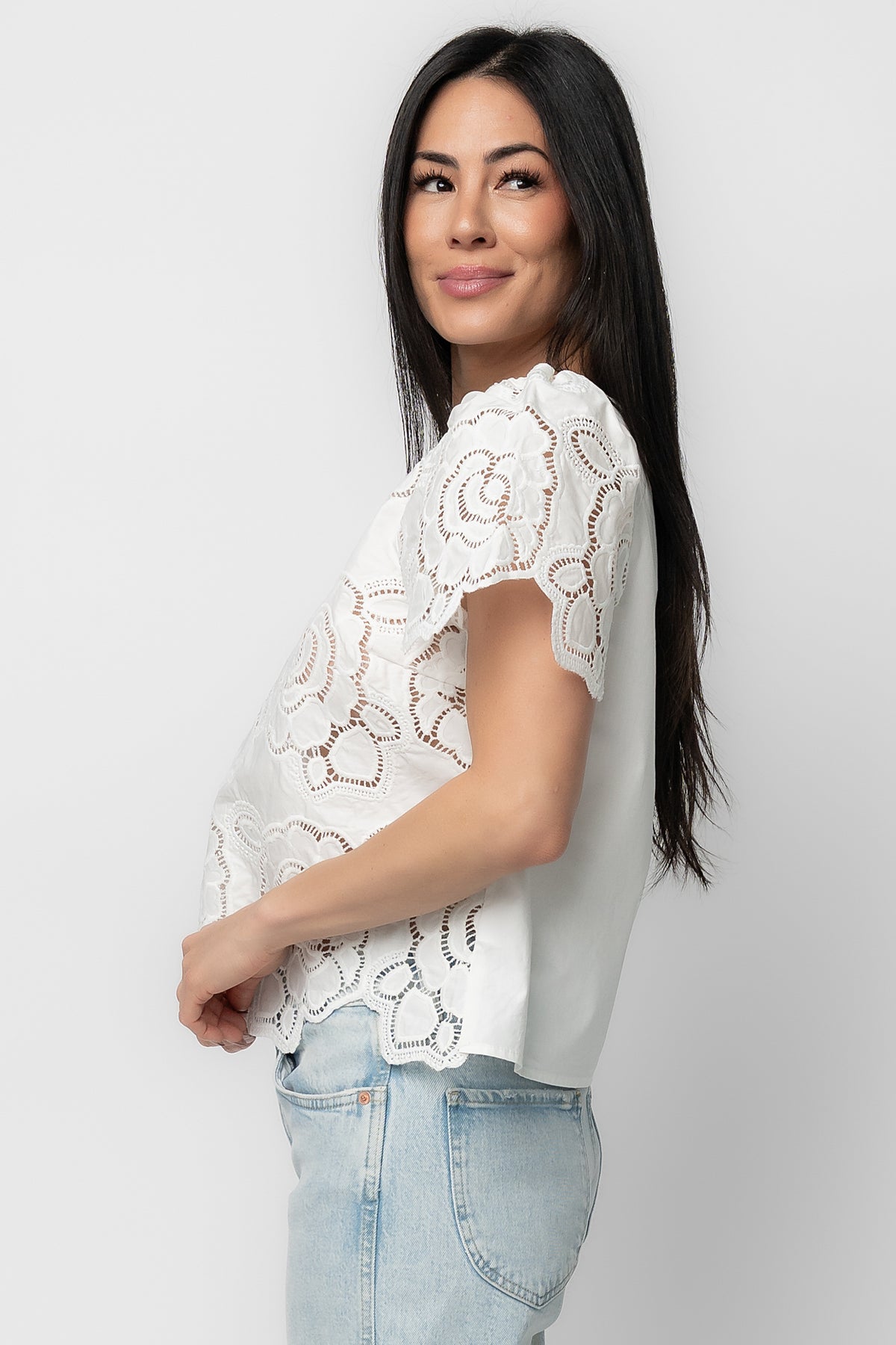 Close-up detail of embroidered eyelet florals and fabric texture on the Delphine Floral Top, showing stitch work and contrast fabric accents.
