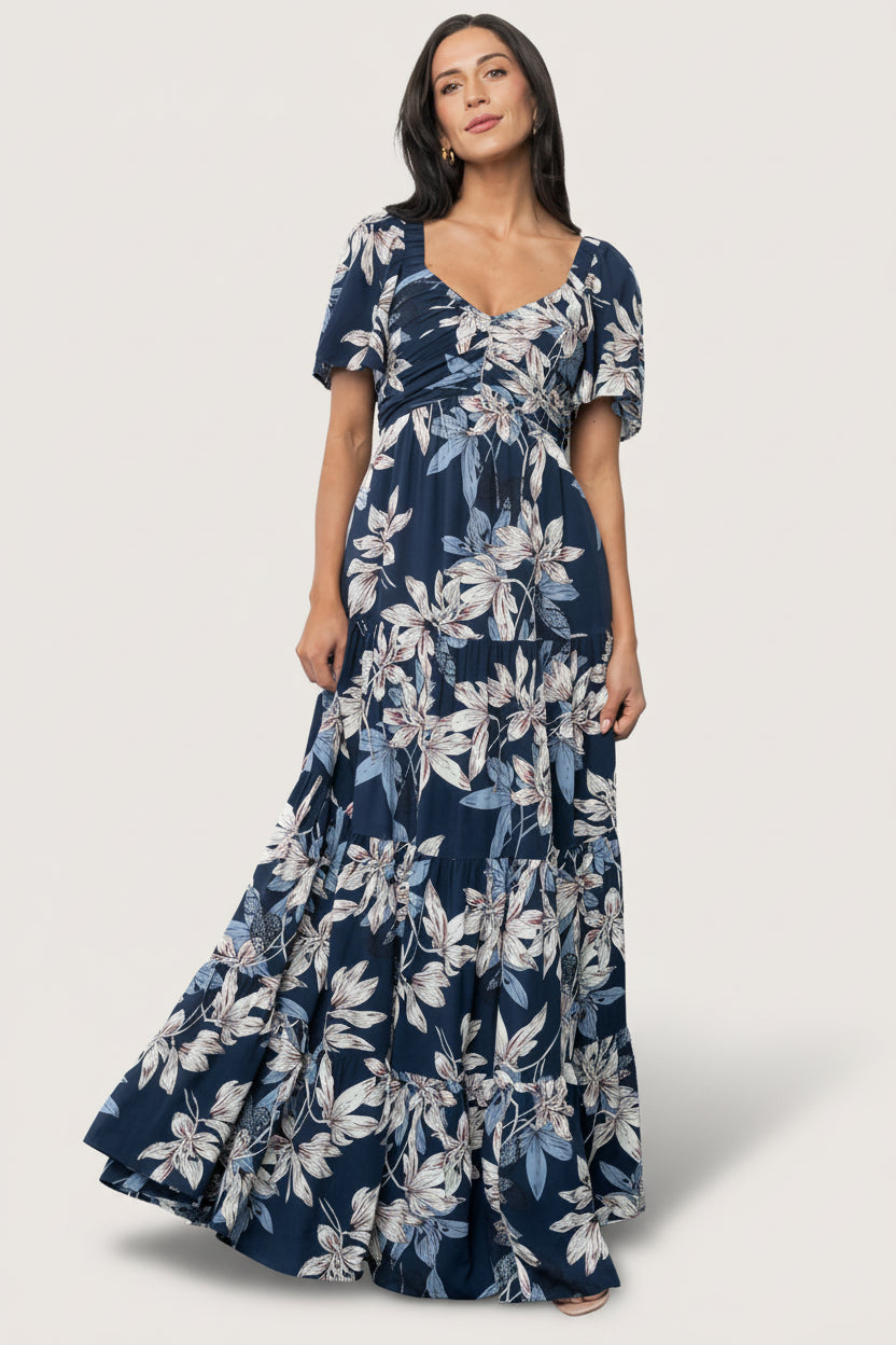 Front view of Villa Maxi Dress in deep navy floral chiffon on mannequin showing wide V-neck, smocked back, and tiered maxi skirt.
