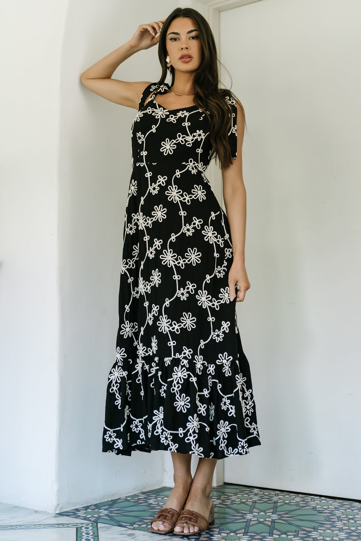Close-up of ivory embroidered floral appliqué on black rayon fabric highlighting texture and embroidered finish.