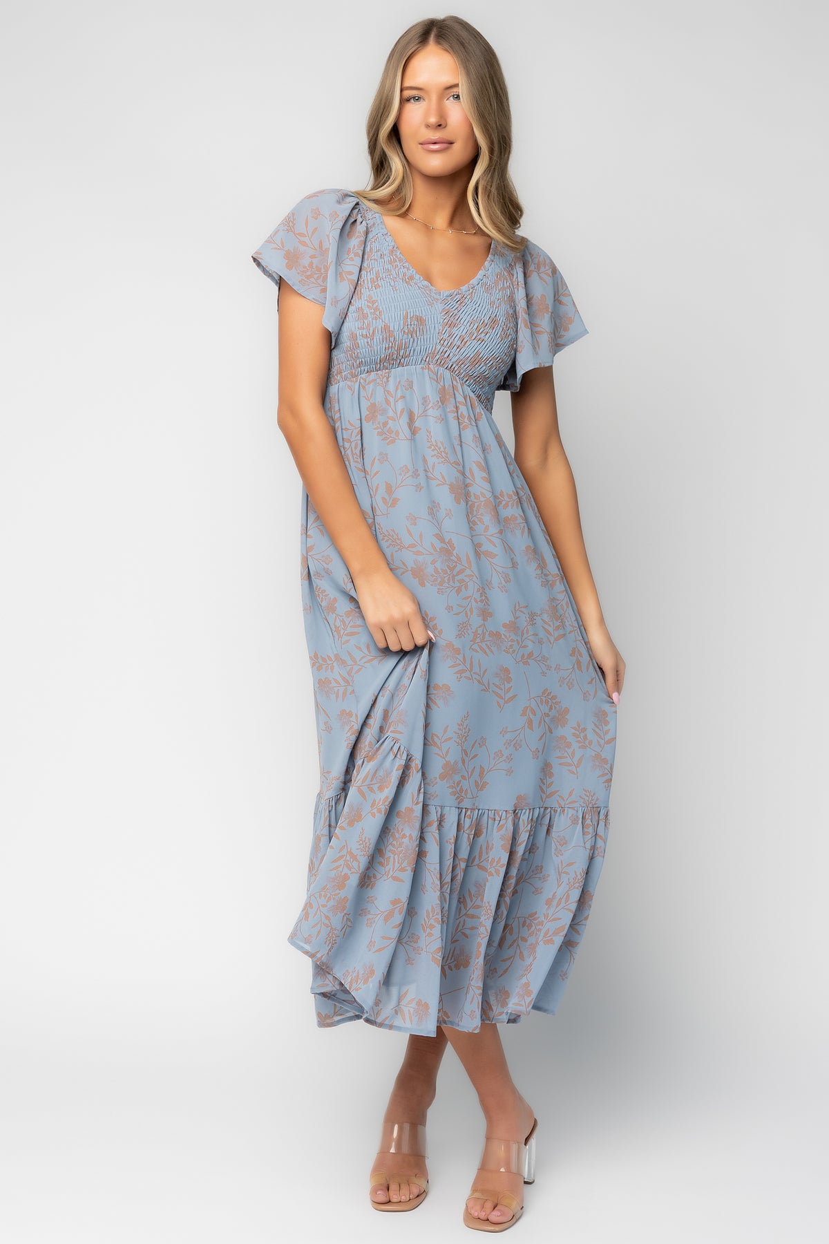 Fabric close-up showing dusty blue base with shimmery terracotta floral print and lightweight polyester weave texture.