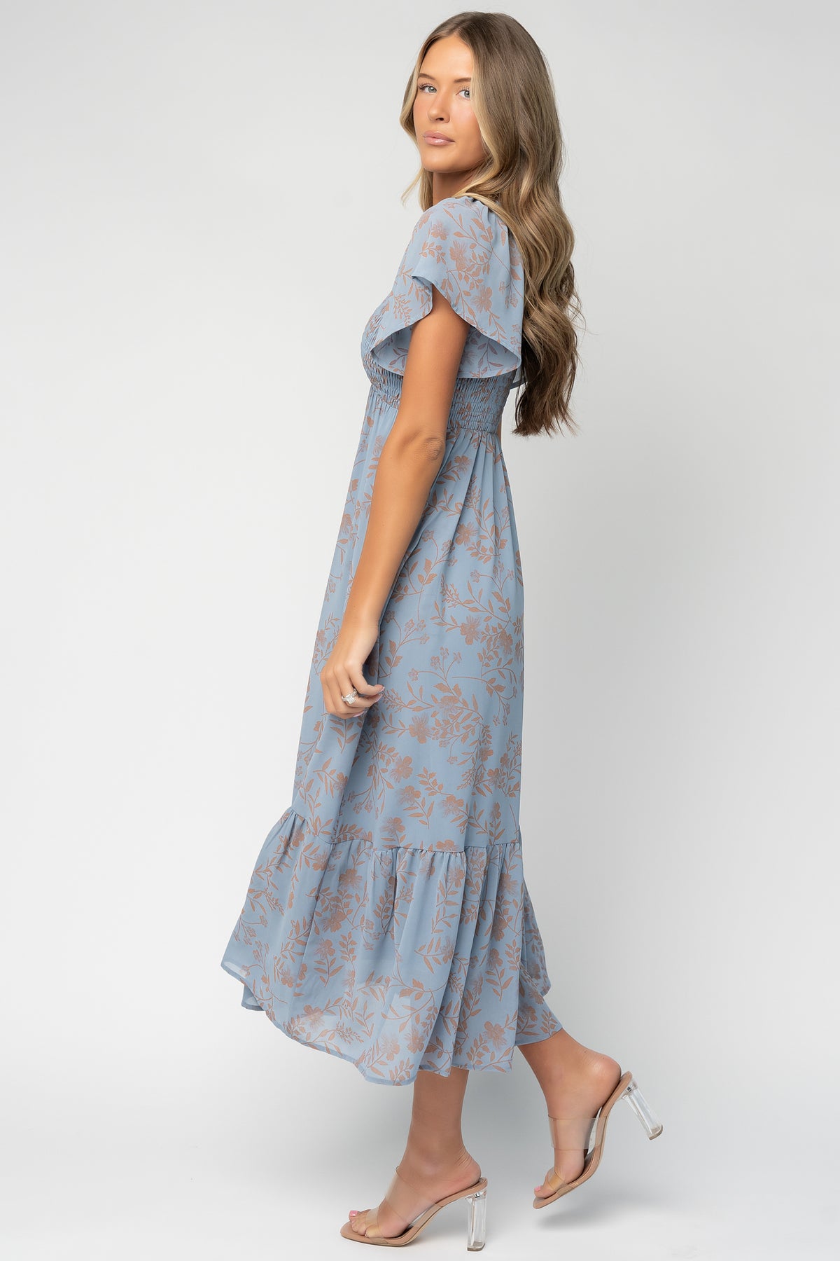 Side view of the Monica dress highlighting flutter sleeve with smocked shoulder detail and the flowing maxi skirt with tier.
