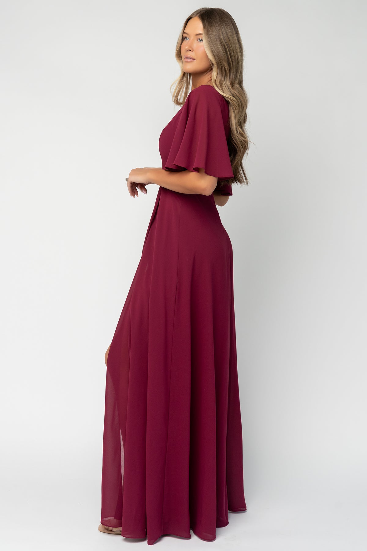 Full-length image of model in wine Valetta Maxi Dress with styling suggestion: strappy heels and minimal jewelry for formal occasions.