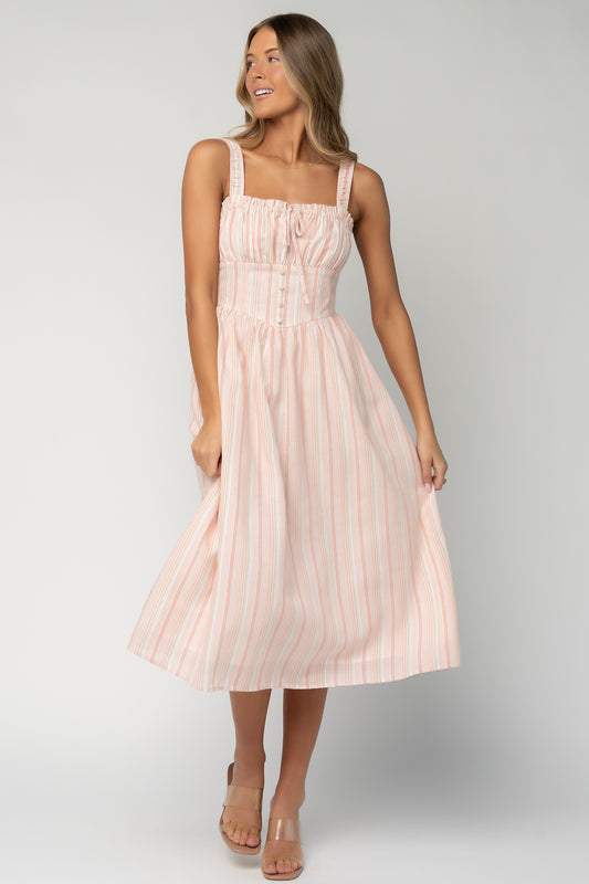 Front view of Melina Midi Dress in peach, green and ivory vertical stripes on model, showing square ruffle neckline, smocked tank sleeves, fitted bodice and midi skirt.