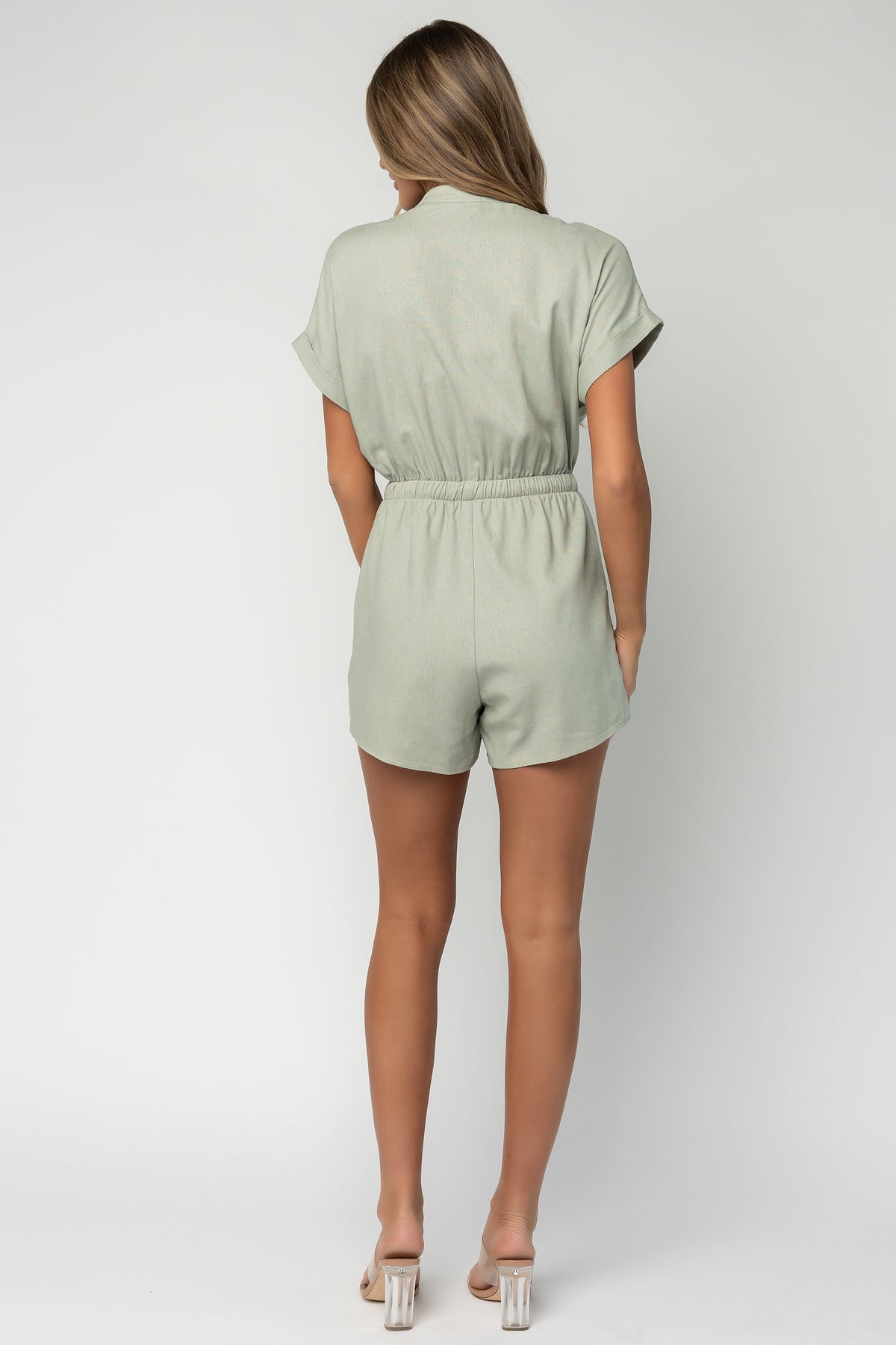 Back view of the Winnie romper in light sage displaying elastic drawstring waistband and fully lined shorts for added coverage.