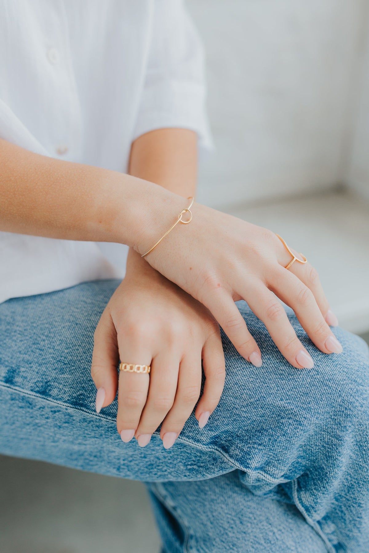 Stacked styling with The Kate Bangle alongside rings, illustrating how the slim gold cuff layers with other pieces for a curated look.