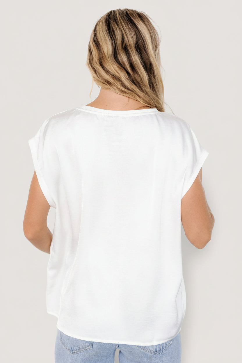 Styled flat-lay of the Adina Top in white displaying round neckline, wide arm openings and oversized cut for versatile pairing.
