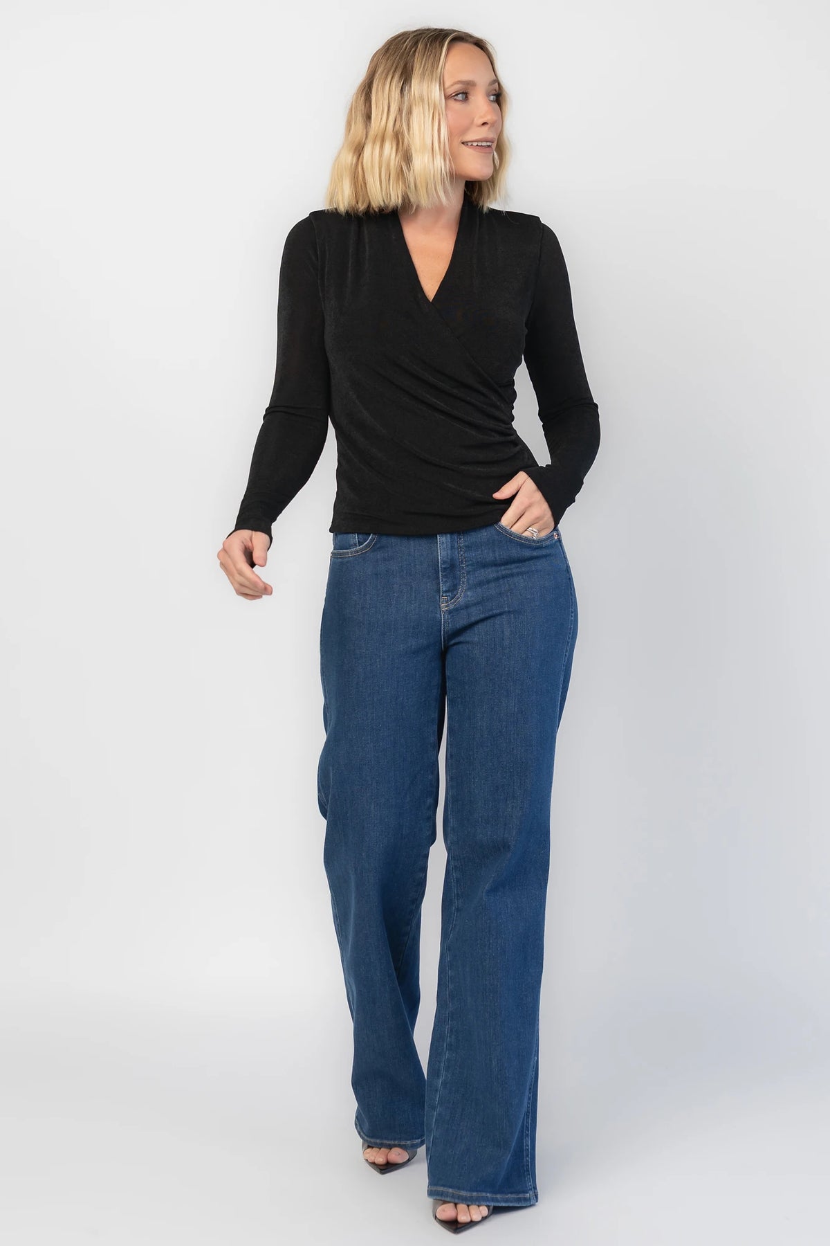 Aelia Top in Black with a plunging V-neckline, crossover front, and ruching along the side.