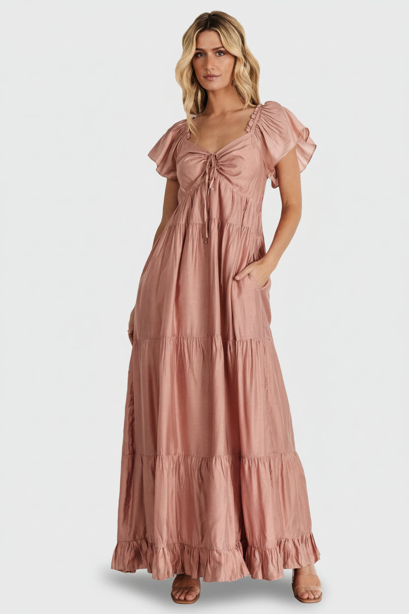Front view of Agatha Maxi Dress in dusty mauve on model; ruffle V-neck, keyhole tie, smocked back and tiered maxi skirt for flowy movement.