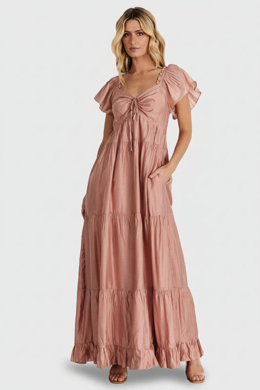 Front view of Agatha Maxi Dress in dusty mauve on model; ruffle V-neck, keyhole tie, smocked back and tiered maxi skirt for flowy movement.