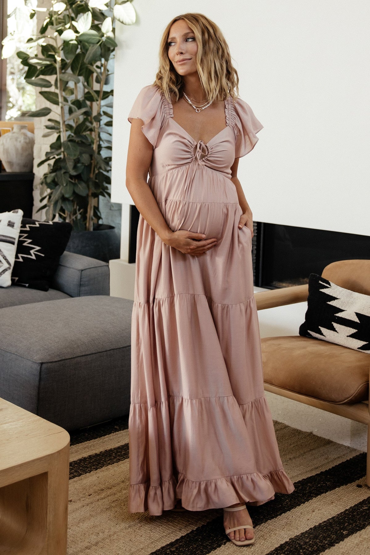 Side profile of Agatha Maxi Dress in dusty mauve on model highlighting short ruffle sleeve, smocked back and tiered skirt silhouette.
