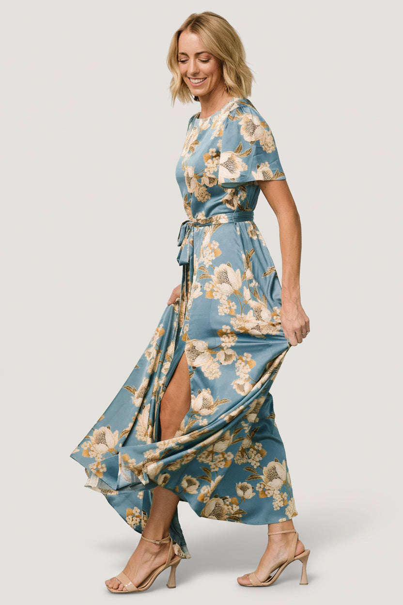 Side view of Agnes satin maxi showing natural waist tie, left leg slit and graceful skirt sweep in teal and gold.