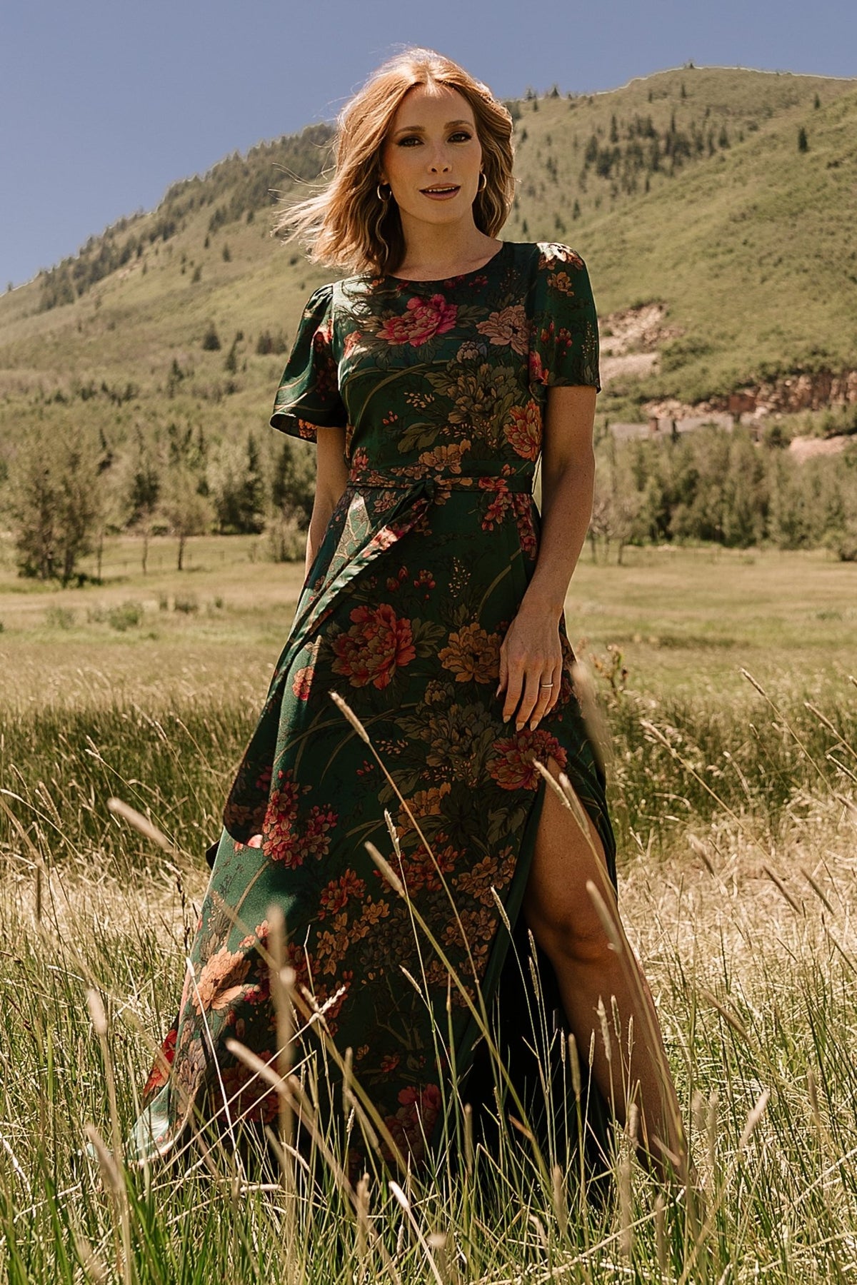 Close-up of dark green floral satin fabric and print showing smooth sheen, multicolor floral details, and stitch finish.