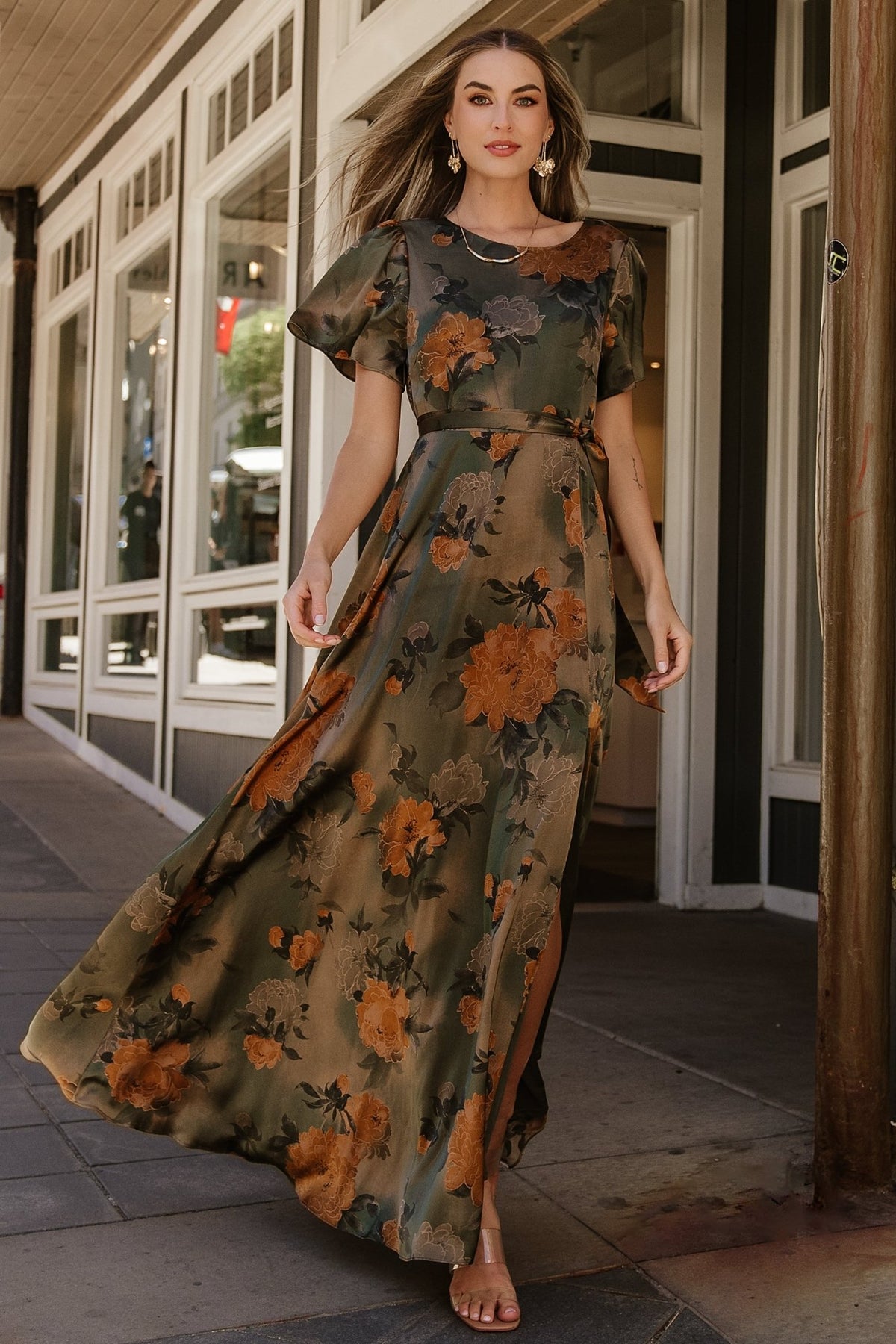Close-up of olive floral satin fabric and print texture with visible sheen and muted apricot and dark green floral accents.