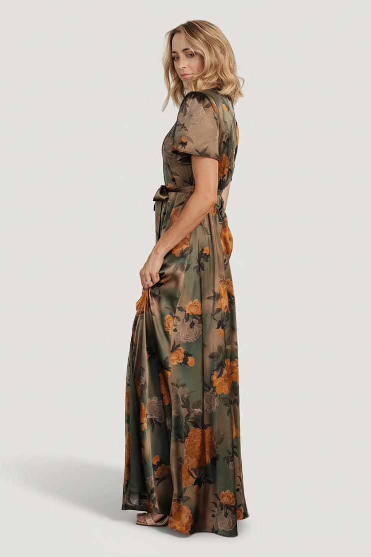 Model shot of olive floral satin maxi dress styled with heels to show length, drape, and how the sash defines the waist.