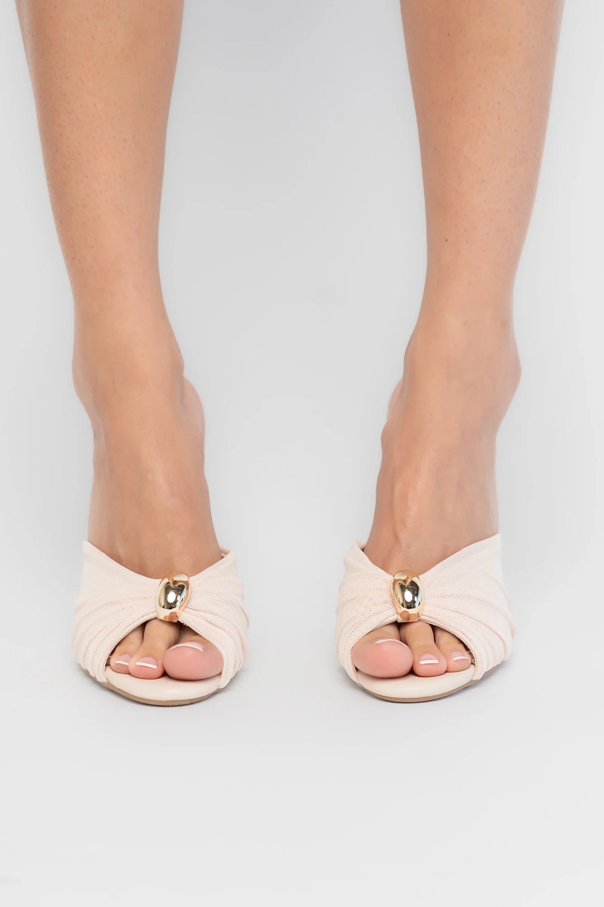 Aiko Slim Stiletto Heel in Natural with pleated fan-style upper, gold-tone accent, open toe, and slim stiletto heel.