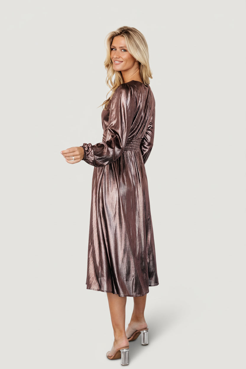 Styled photo of model wearing the bronze Aisha shimmer midi dress for a special occasion, paired with simple heels.