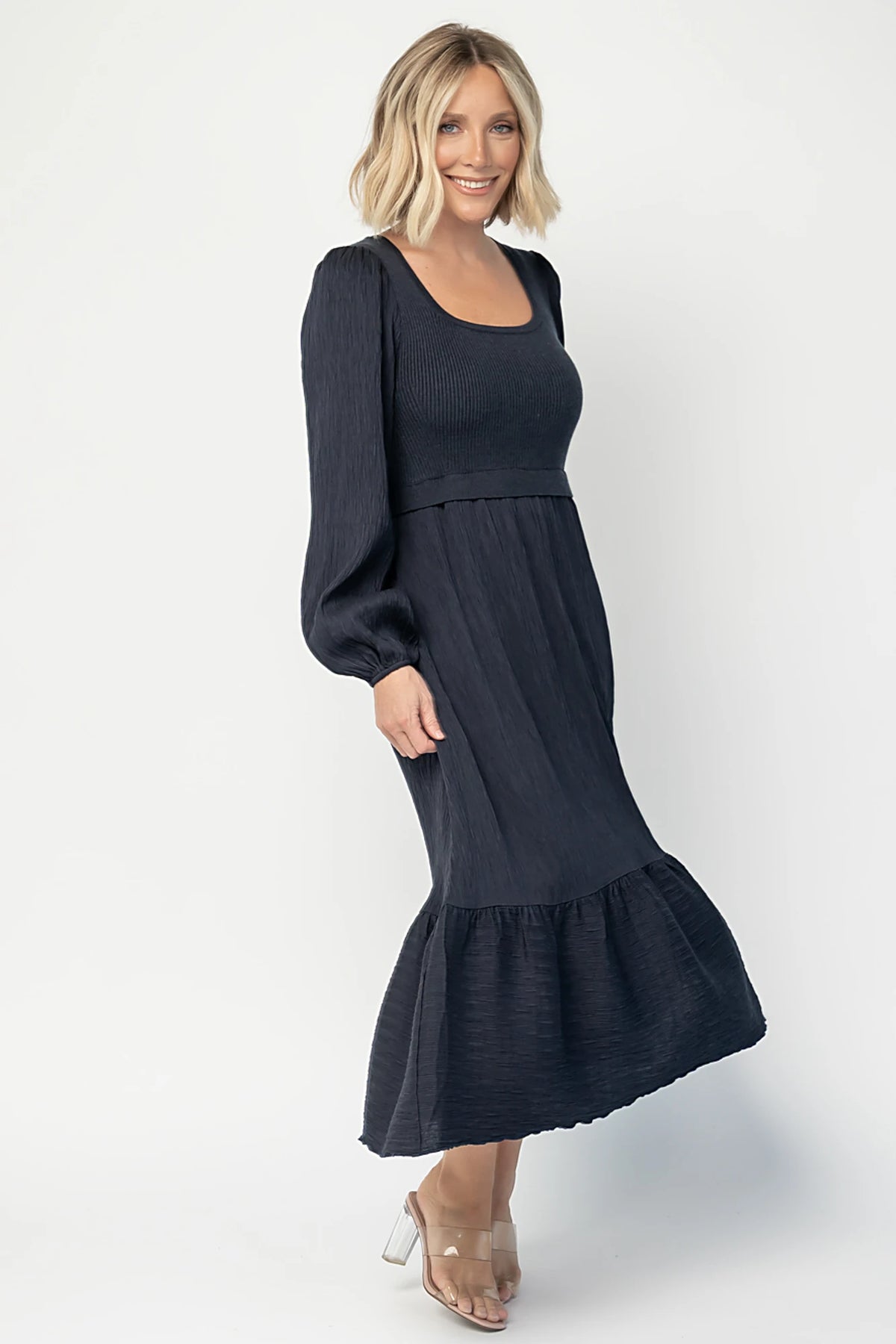 Alva Sweater Dress in Dusty Navy with ribbed knit bodice, square neckline, ruffle shoulders, long sleeves, and midi skirt.