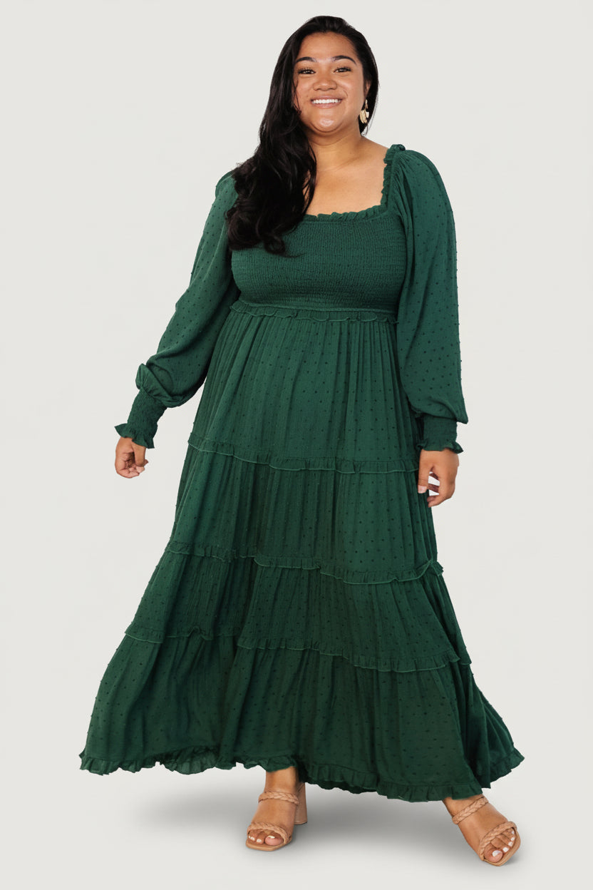 Front view of evergreen smocked dotted maxi dress on model showing square neckline, long sleeves, smocked bodice, and flowing full-length skirt.