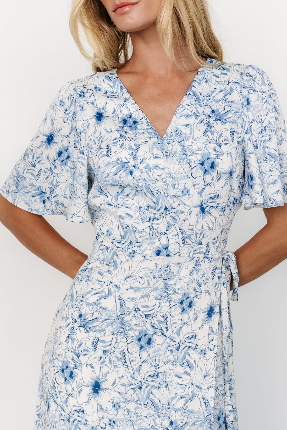 Close-up of blue floral crepe fabric and skirt drape on Amelie Wrap Midi Dress, highlighting lining and subtle texture.