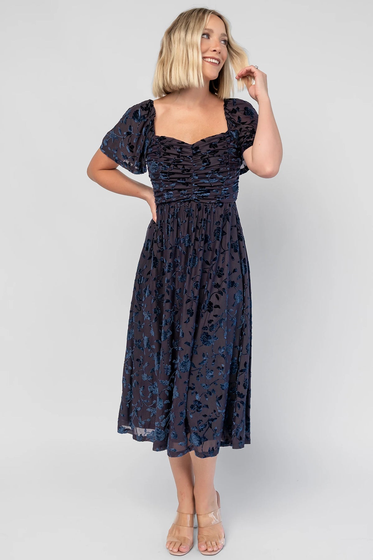 Amoret Midi Dress in Midnight Navy Floral with raised velvet florals, a sweetheart neckline, and flutter sleeves.