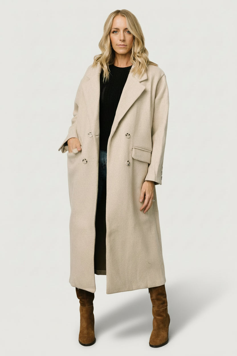 Front full-length view of Anderson double-breasted coat in natural, showing lapel collar, double-breasted buttons, brushed fabric texture, and side pockets.