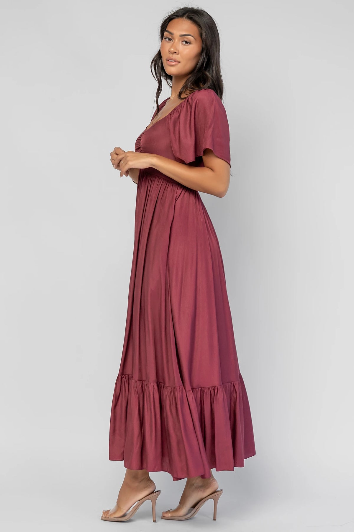 Anisa Midi Dress in Burgundy with a wide V-neckline, cinched bust, elastic shoulders, and a tiered skirt.