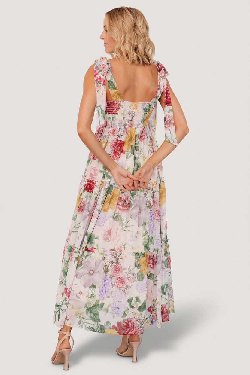 Detail shot of three ruffled tiers and hem movement on the blush multi floral chiffon maxi dress, showing fabric texture.