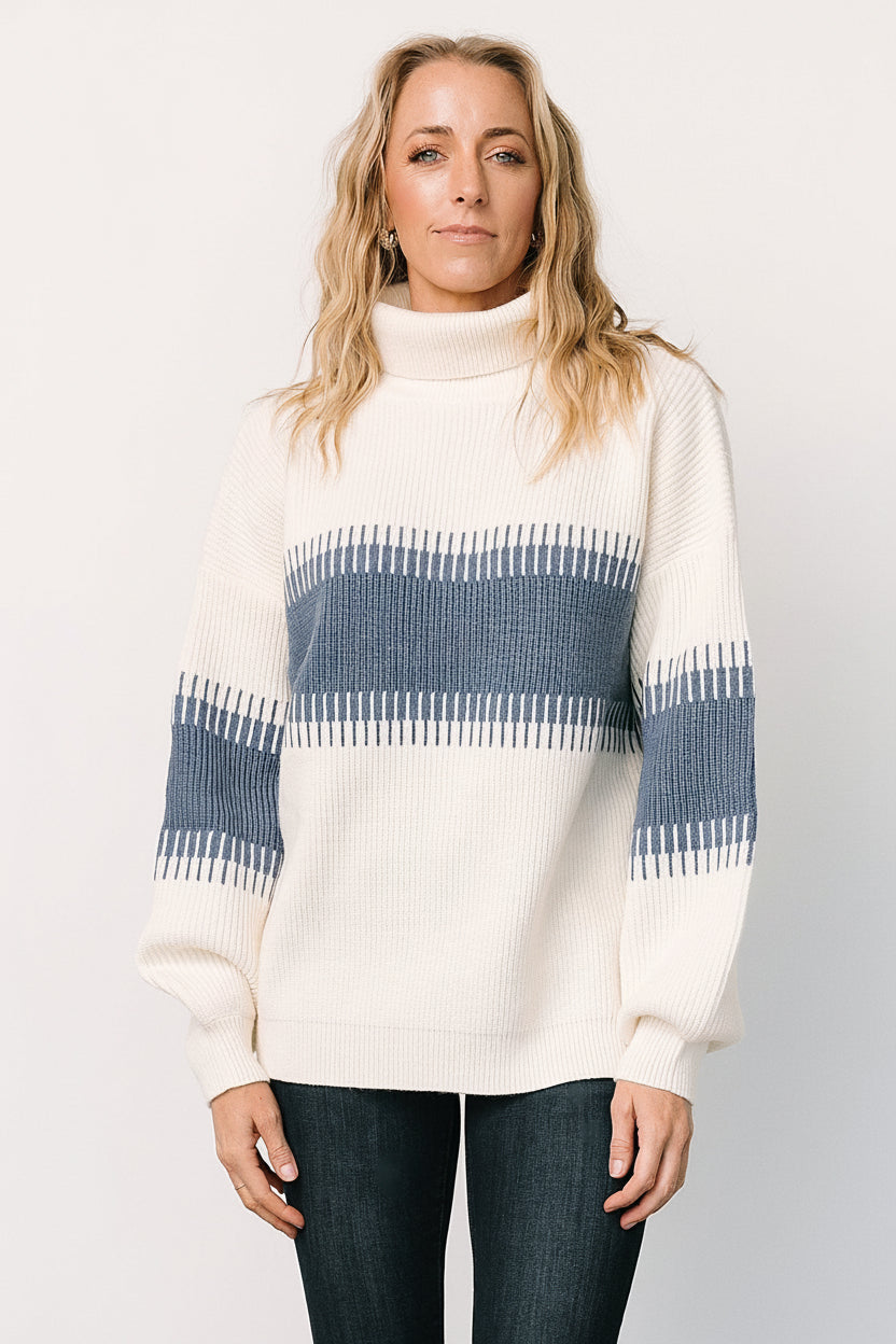 Studio image of the Antonov blue and cream sweater on a neutral background, showing overall shape, color contrast, and the high neckline silhouette.