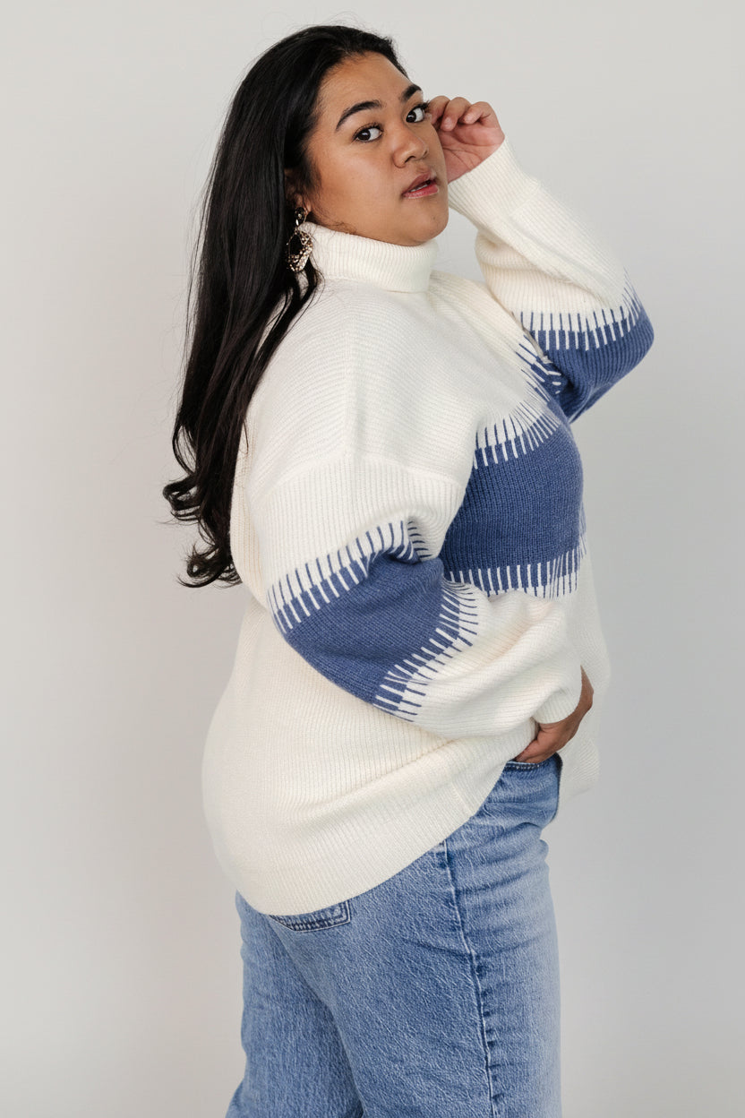 Styled outfit photograph showing the Antonov turtle neck sweater layered over a tee, highlighting how the oversized fit pairs with slim bottoms.