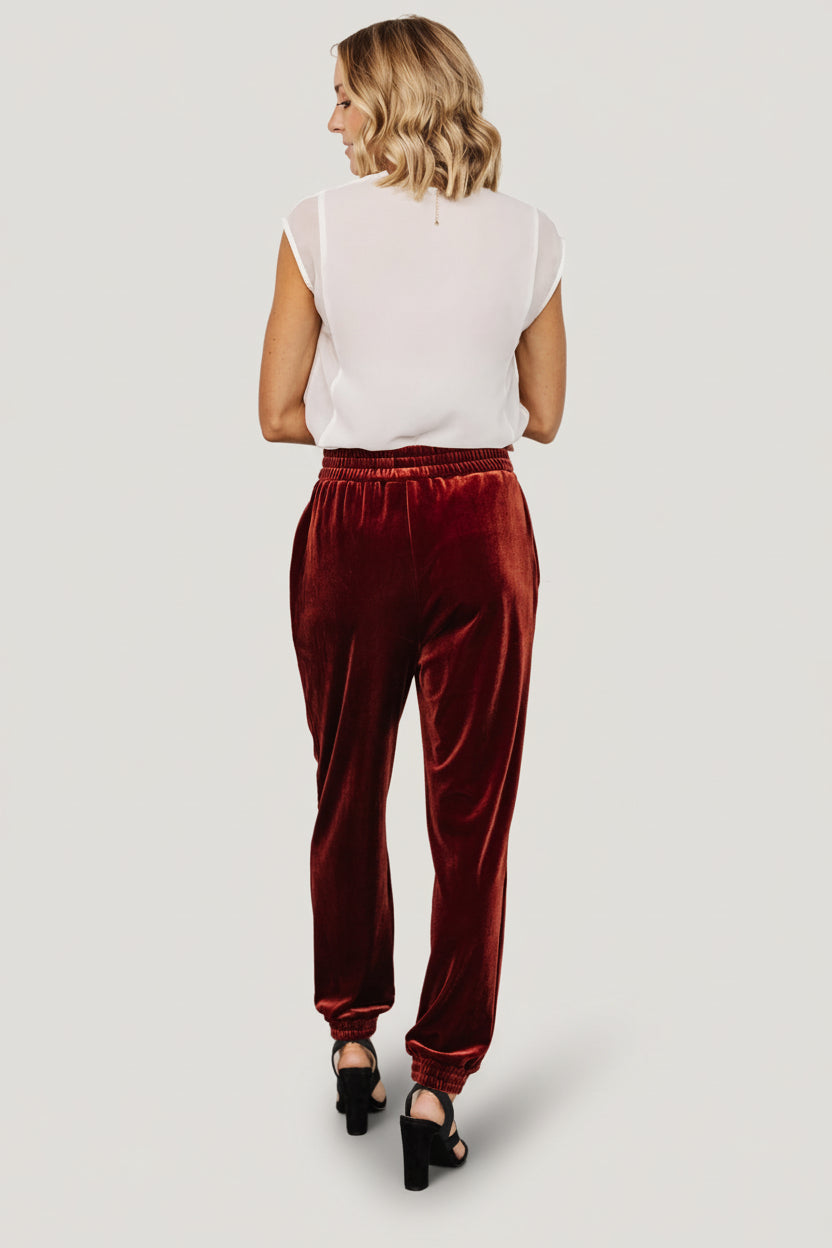 Folded view of Archie velvet jogger pants in cinnamon, emphasizing fabric drape and color depth in a flat-lay presentation.