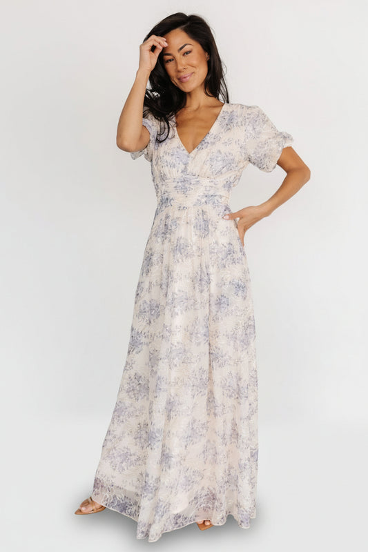 Front view of cream and slate-blue floral maxi dress with gold embroidered accents, V-neck and short puff sleeves, showing full silhouette.