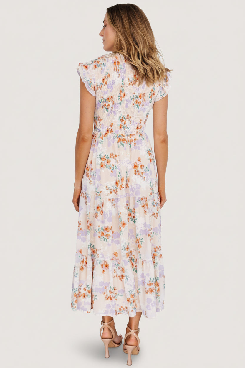 Back view of cream floral chiffon maxi dress showing tiered skirt and smocked back detail, lightweight silhouette on model.