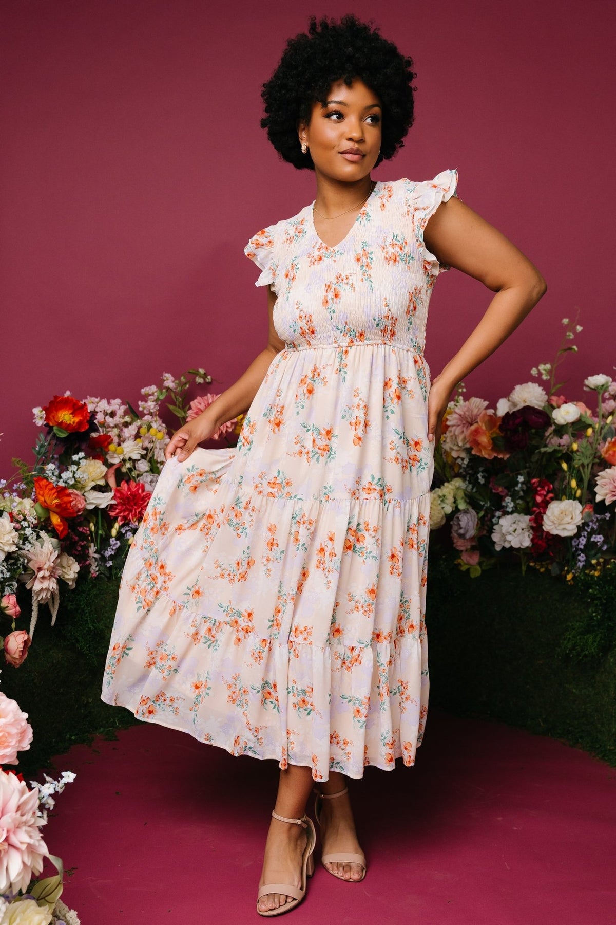 Three-quarter view of cream floral smocked maxi dress styled with gentle movement in the tiered skirt, full lining visible.