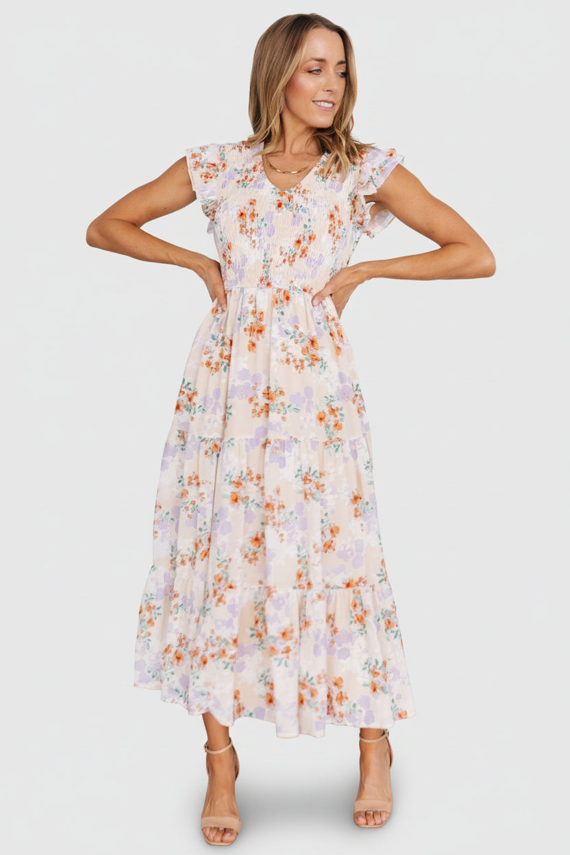 Close-up of smocked bodice and V-neck on cream floral chiffon dress, highlighting fabric texture and stitching detail.