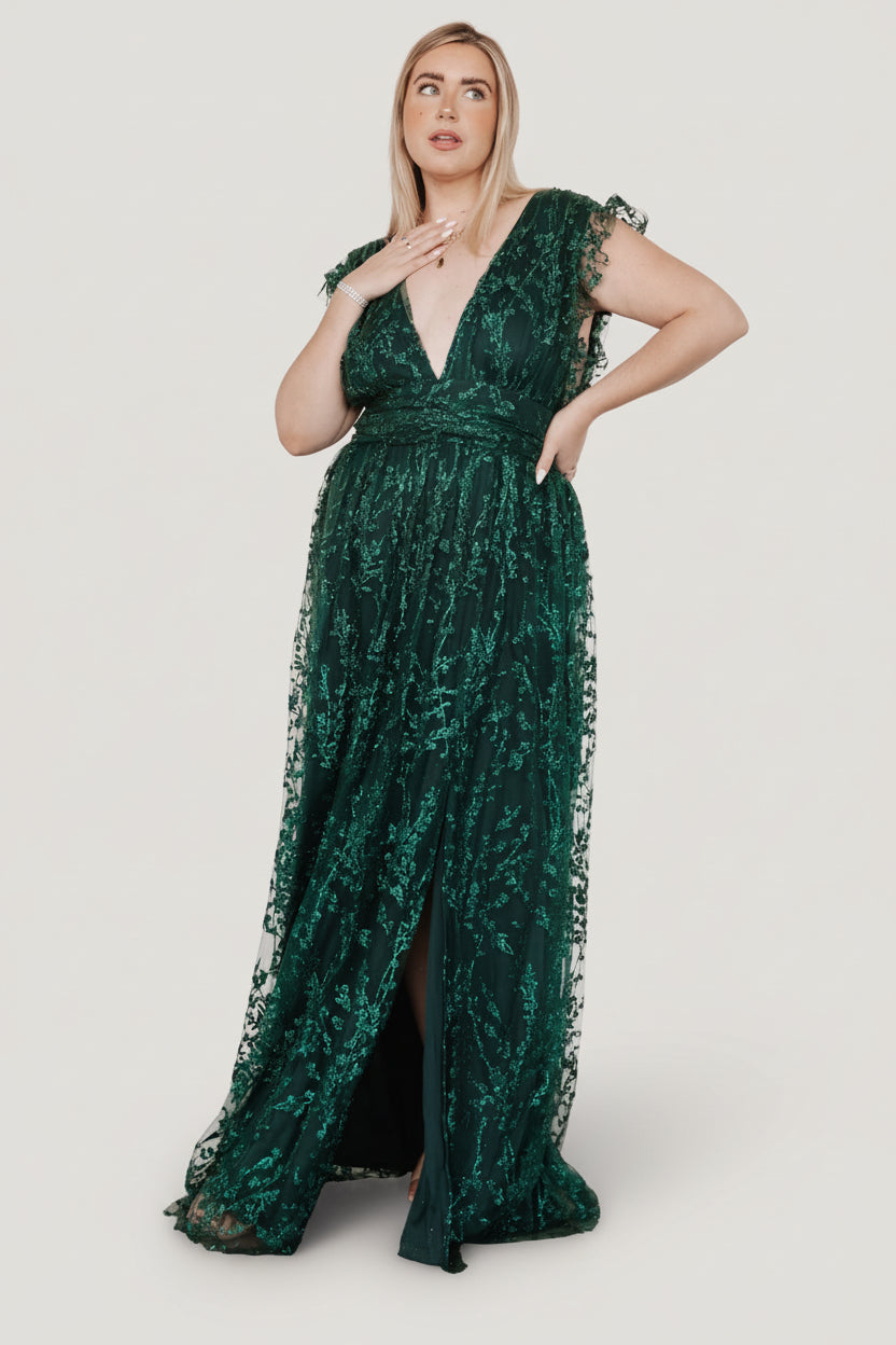 Side view of emerald Arlene Shimmer Gown highlighting tulle sleeve frill, leg slit, and flow of the shimmer tulle overlay across the maxi skirt.