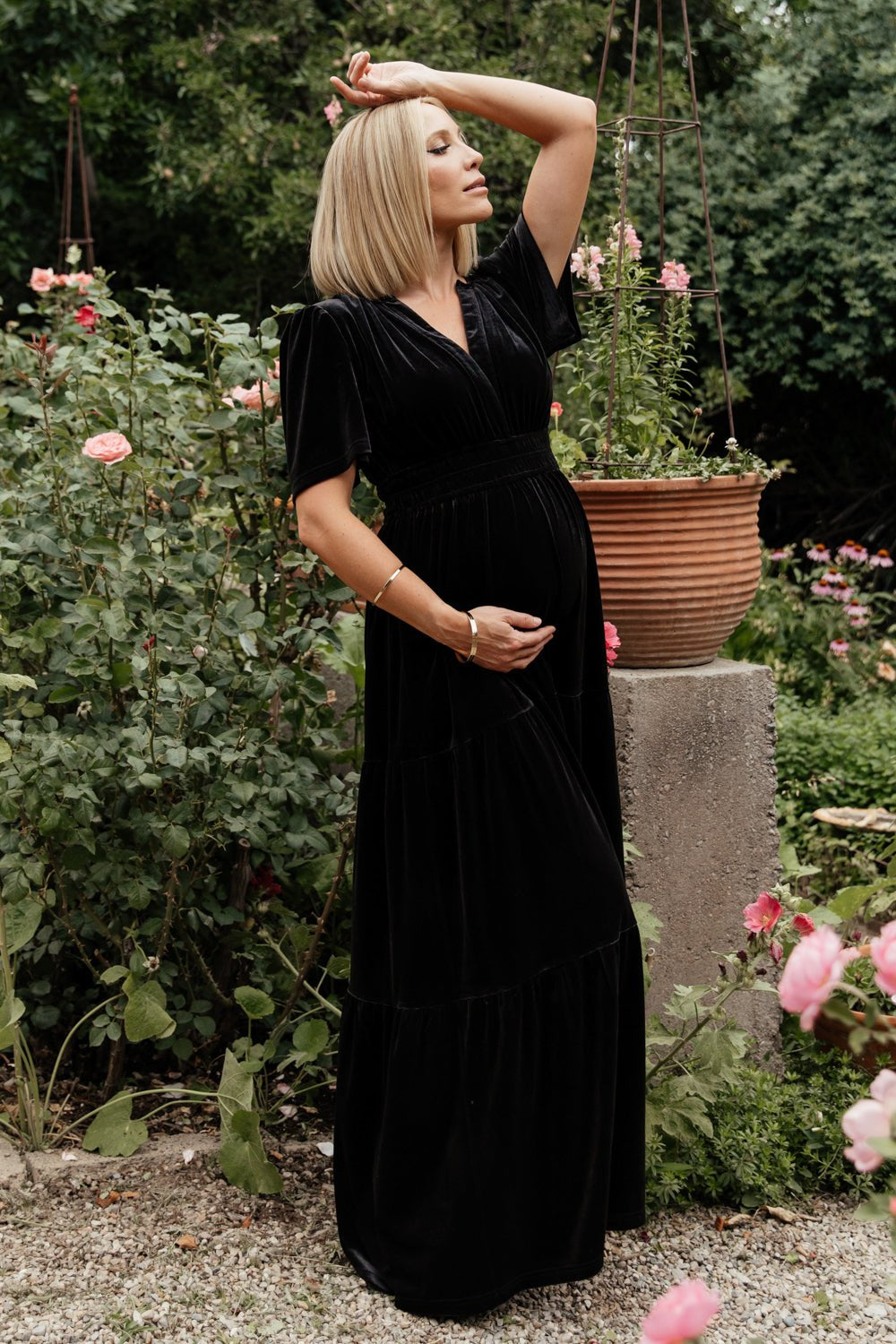 Side view of Artemis black velvet maxi dress showing flutter sleeve detail, plunging V-neckline, and flowing tiered skirt.