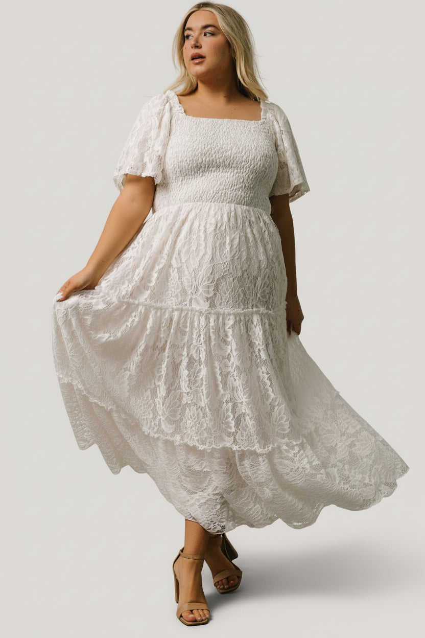 Close-up of lace fabric and smocked bodice on off-white maxi, highlighting lace pattern and neutral inner lining for coverage.