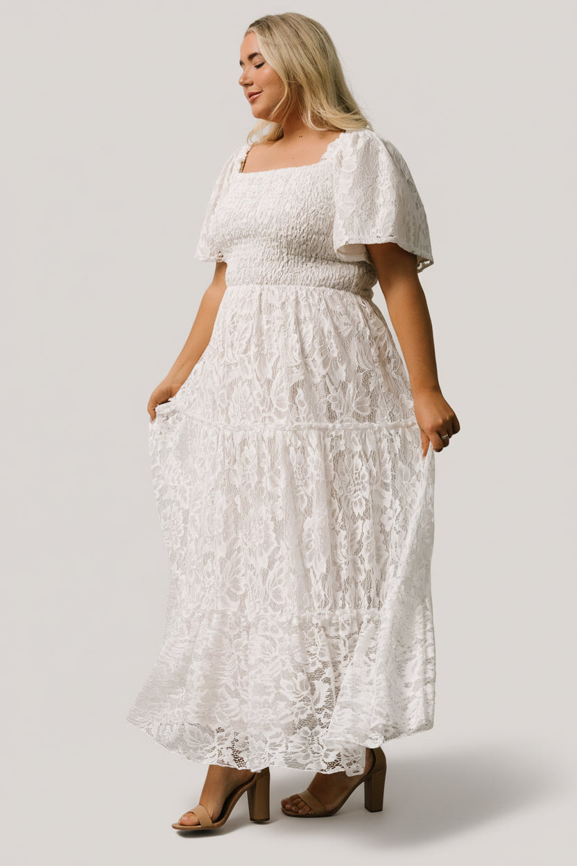 Studio detail shot of off-white lace maxi focusing on sleeve hem, ruffle trim, and textured lace overlay fabric.