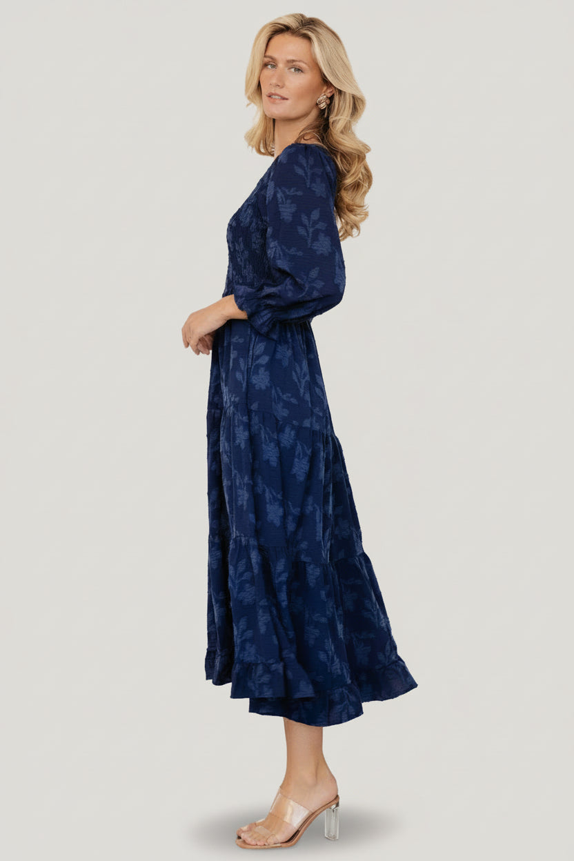 Side view of the navy floral midi dress showing hidden pocket placement, elastic waistline, and tiered skirt silhouette.