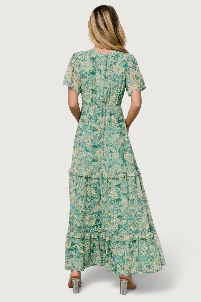 Detail shot of skirt and hemline showing layered ruffles and chiffon fabric movement with green and yellow floral pattern visible.