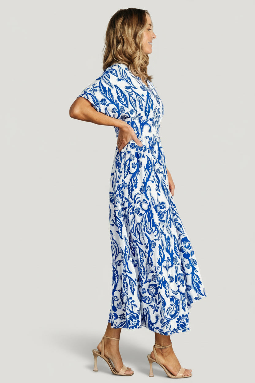 Model wearing cobalt-print midi dress styled with sandals, showing tiered skirt movement and relaxed silhouette.