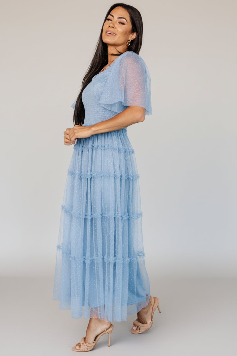 Styled look of dusty blue Bexley tulle midi dress with minimal accessories, showcasing mid-length ruffle tiers and event-ready silhouette.