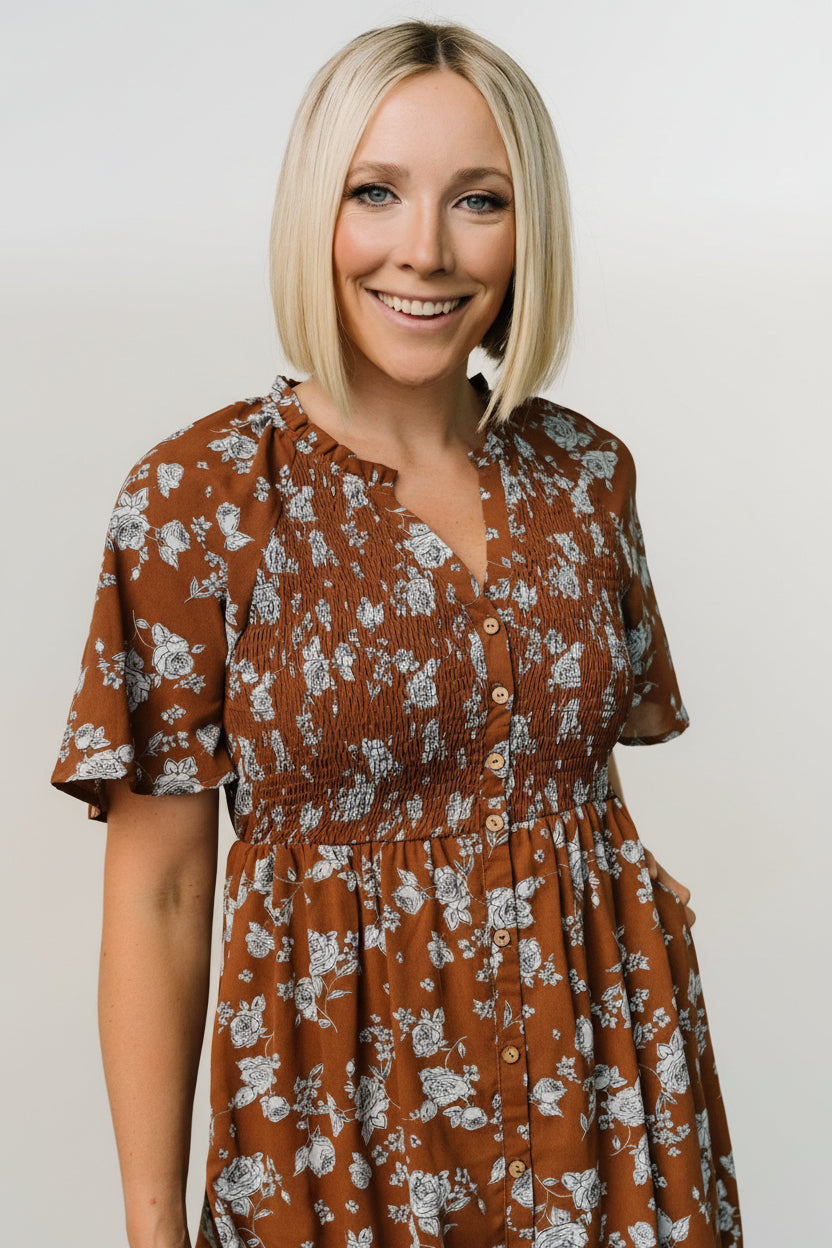 Three-quarter view of brown and blue floral midi showing short sleeves, elasticized waist, smocked bodice, and soft drape of the lined skirt.