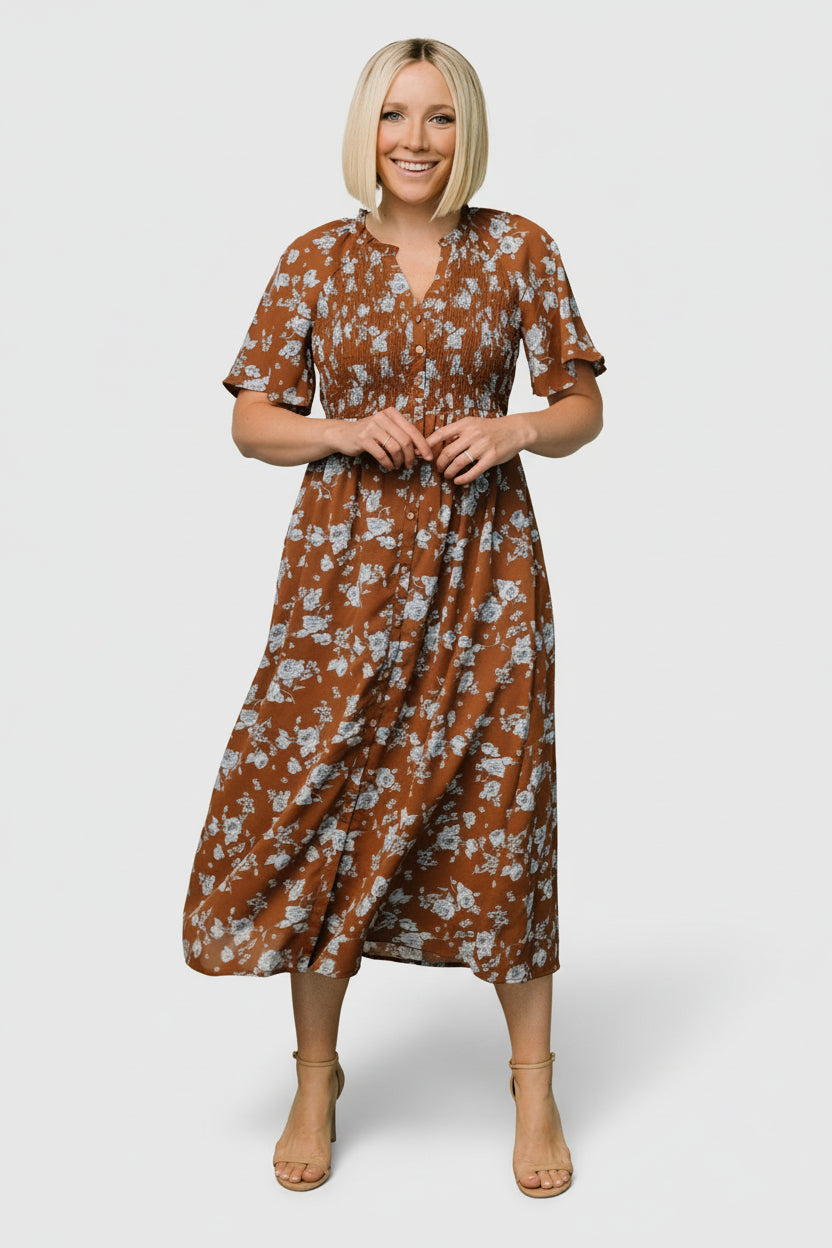 Back view of the floral midi dress displaying the elasticized waist, button-back detail, and the skirt’s soft movement and coverage.