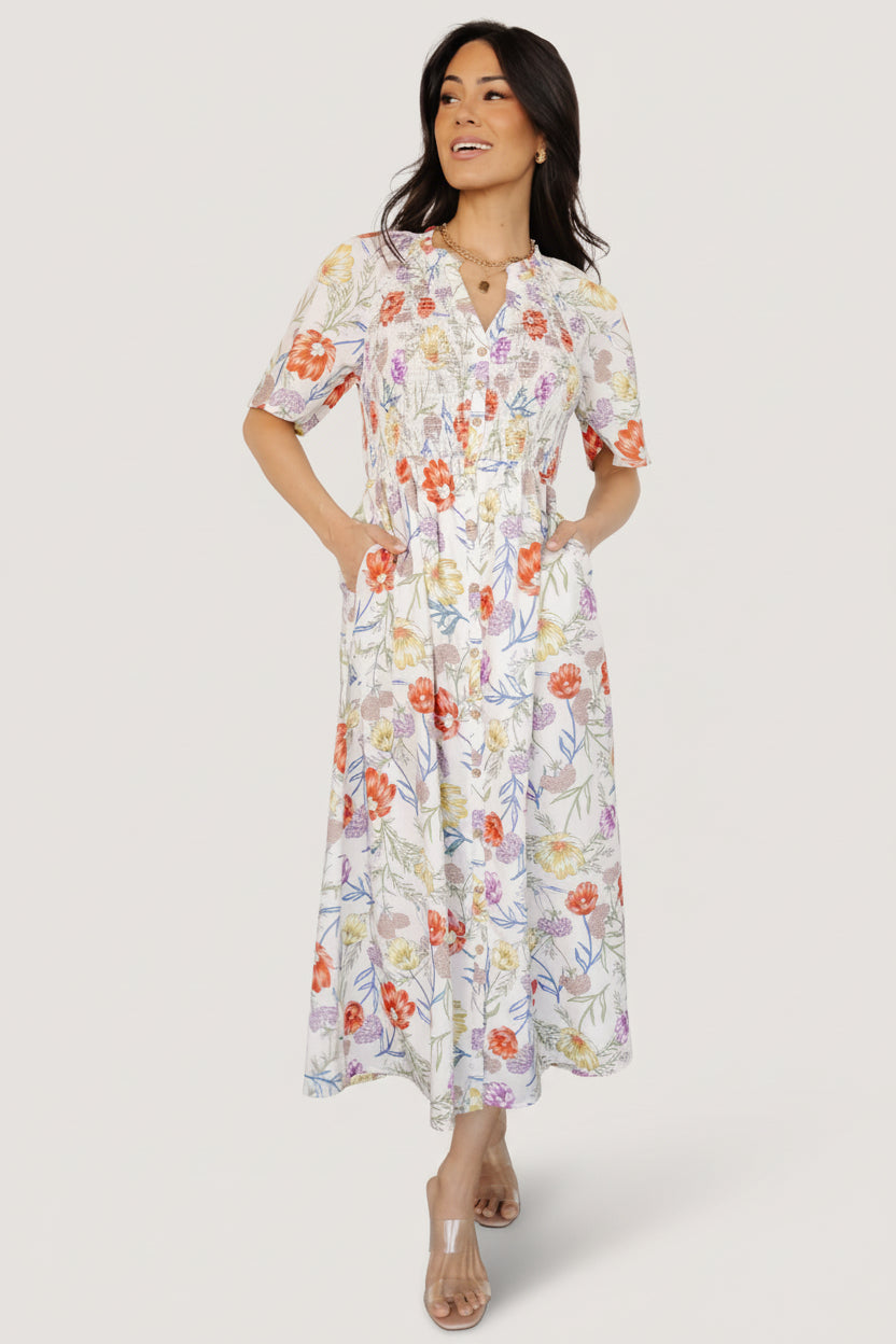 Front view of ivory floral rayon midi dress with ruffled notched neckline, smocked front bodice, elastic waist, and attached lining, on white background.